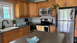 Una cocina moderna con armarios de madera, electrodomésticos de acero inoxidable y una isla central.