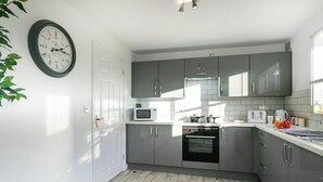Una cocina moderna con armarios grises, un microondas blanco y un horno empotrado.