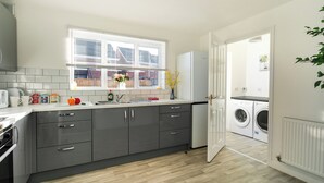 Una cocina moderna con armarios grises, una encimera blanca y una ventana con persianas.