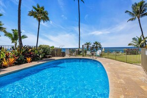 A clear blue swimming pool surrounded by palm trees and a stone deck. - Oceanfront 2Bd 2Ba Air Conditioned Suite in South Maui (Kihei)