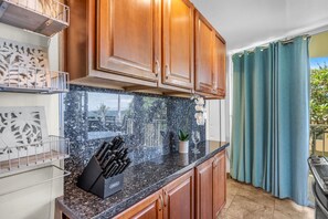 A kitchen with wooden cabinets, a granite countertop, and a knife block. - Oceanfront 2Bd 2Ba Air Conditioned Suite in South Maui (Kihei)