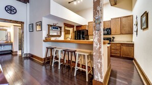 Una cocina con armarios de madera, un refrigerador y una barra con taburetes.
