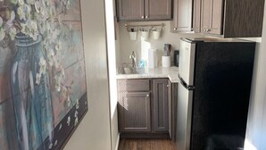 Una cocina compacta con muebles de madera oscura, un refrigerador de acero inoxidable y una pequeña encimera.