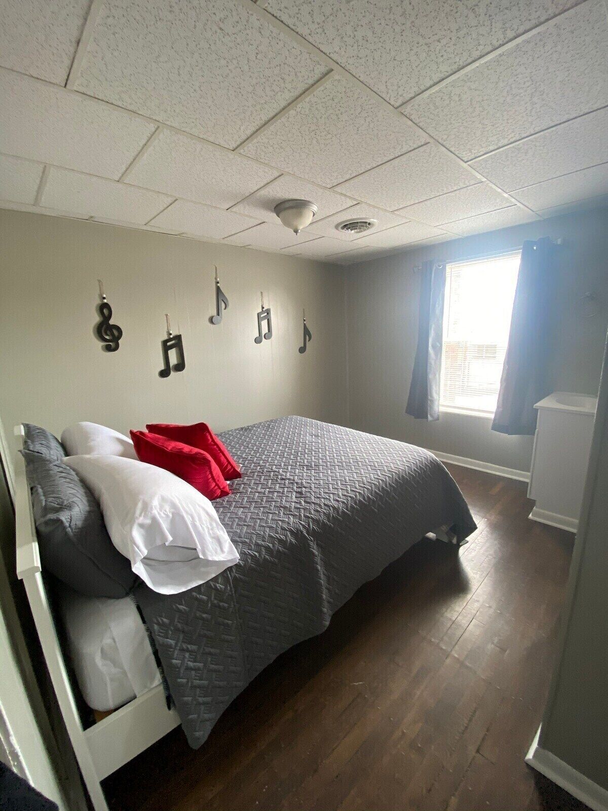 A bedroom with a bed, pillows, a window, and a wall with musical notes.