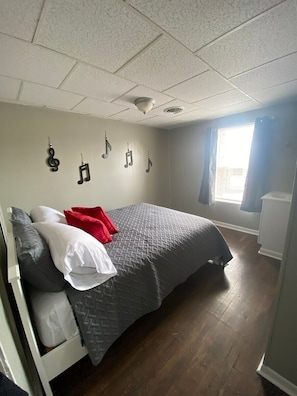 A bedroom with a bed, pillows, a window, and a wall with musical notes.
