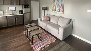 Un salon moderne avec un canapé gris, une table basse et un tapis coloré.