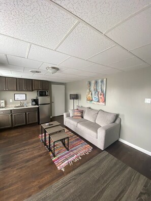 A modern living room with a grey sofa, a coffee table, and a colorful rug.