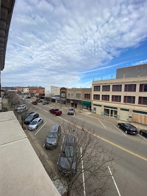 A street view with parked cars, buildings, and a clear sky.