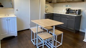 A compact kitchen with a wooden table and matching stools, a microwave, and cabinets. - Beach themed, newly renovated 1 bedroom apartment (Coshocton)