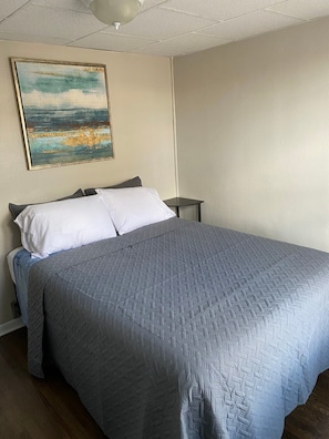 A bedroom with a large bed, a nightstand, and a painting on the wall. - Modern apartment in downtown Coshocton (Coshocton)