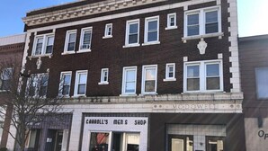 Un edificio a due piani con un negozio di abbigliamento maschile al piano terra, chiamato "Carroll's Men's Shop", e un ufficio al secondo piano, denominato "McDowell".