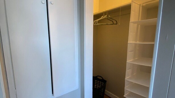 Armadio a muro con porta bianca, pavimento in legno e appendiabiti.