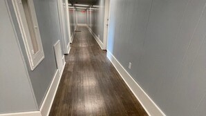A long, narrow hallway with wooden flooring and light blue walls. - 1 Bedroom Apartment in Downtown Coshocton (23) (Coshocton)