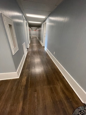 A long, narrow hallway with wooden flooring and light blue walls.