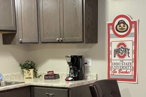 Une cuisine équipée de placards, d’une machine à café, d’une plante et d’une affiche des Buckeyes.