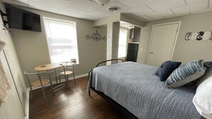 A bedroom with a bed, a desk, and a chair. - Studio Apartment on Main Street in Coshocton (35) (Coshocton)