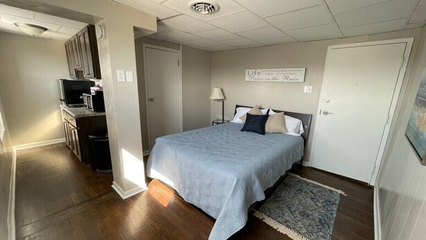 A bedroom with a bed, a nightstand, a lamp, and a wall with a motivational quote. - Studio Apartment on Main Street in Coshocton (26) (Coshocton)