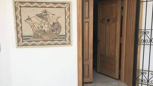 A wooden door with a metal gate, a tiled floor, and a framed picture of a ship on the wall. - Magnificent waterfront villa + Kerkennah swimming pool (bounouma)