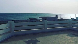 A coastal walkway with a white railing, a bench, and a small structure. - Magnificent waterfront villa + Kerkennah swimming pool (bounouma)