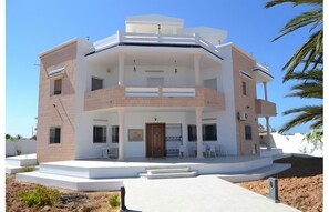 A multi-story building with a central courtyard, balconies, and a flat roof.