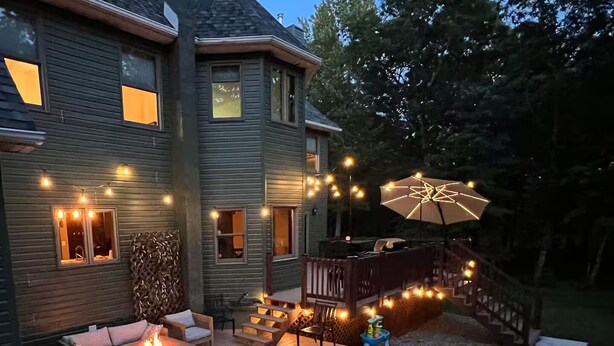 Una casa con jacuzzi, mobiliario exterior e iluminación con luces colgantes.