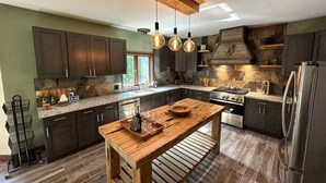 Una cocina moderna con gabinetes oscuros, una isla de madera y un salpicadero de piedra.