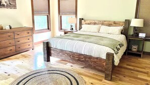 Un dormitorio con una cama y cómoda de madera, además de una mesita de noche con una lámpara.