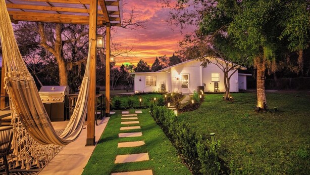 A house with a covered patio, a hammock, and a grill.