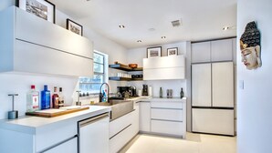 A modern kitchen with white cabinetry, a built-in oven, and a refrigerator.