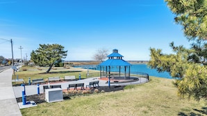 A gazebo with a blue roof overlooking a lake, benches, and a pathway.