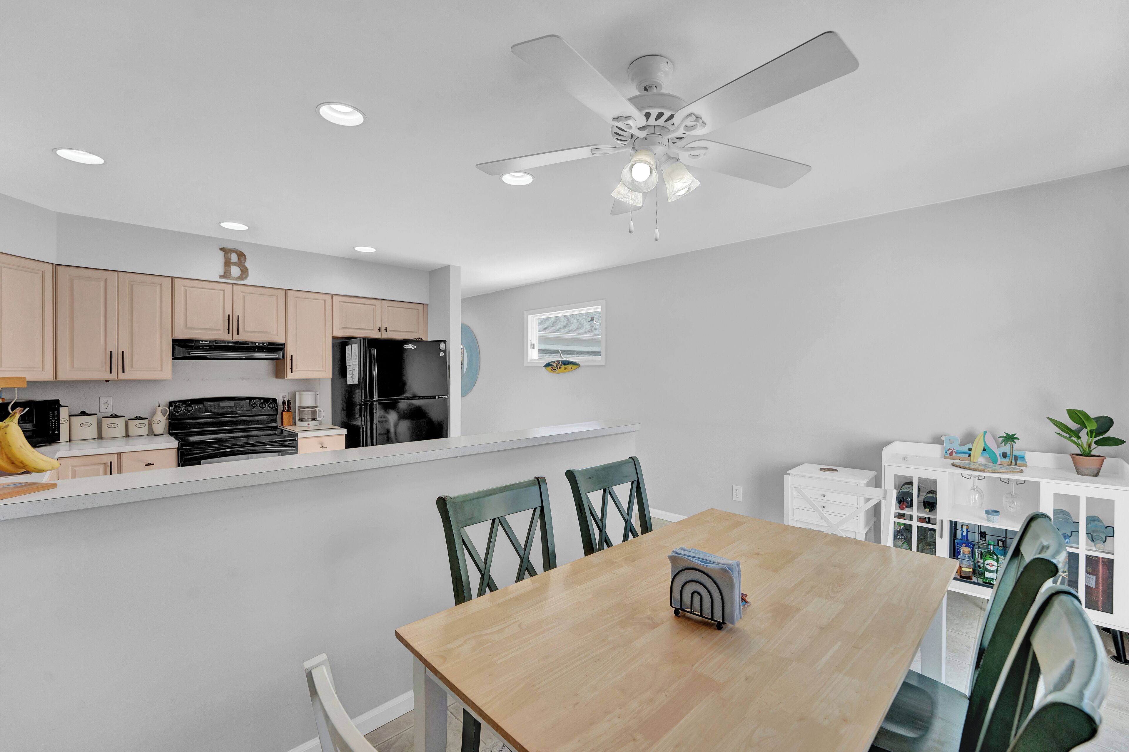 A modern kitchen with a dining area, a ceiling fan, and a window.