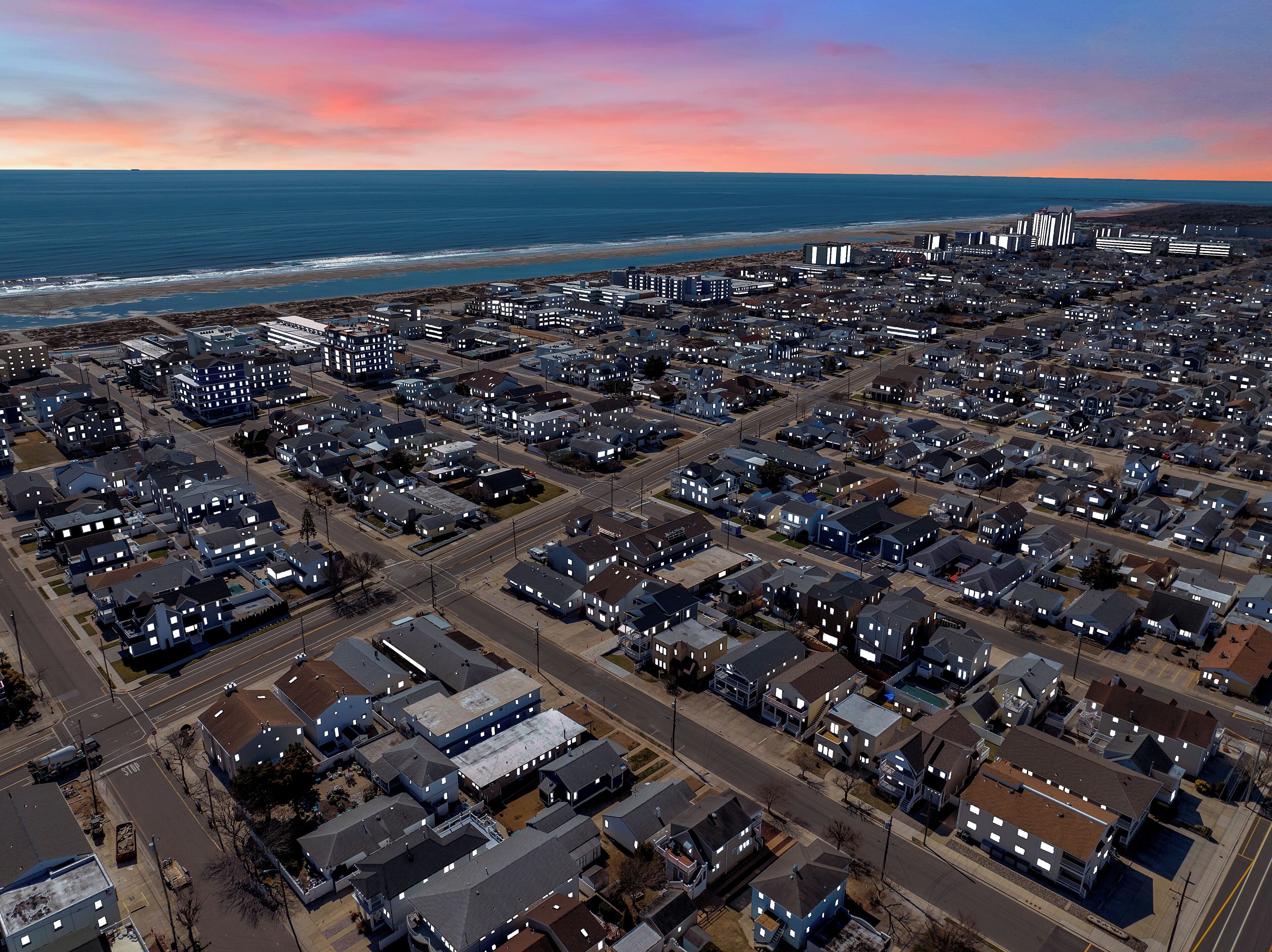 Vista aérea de una zona residencial con casas, carreteras y una playa al fondo.