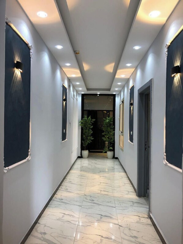 A hallway with marble flooring, recessed lighting, and potted plants. - Royal Season Hotel (Cairo)