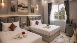Ein modernes Hotelzimmer mit zwei Betten, einem großen Fenster mit Vorhängen und Bildern an den Wänden.