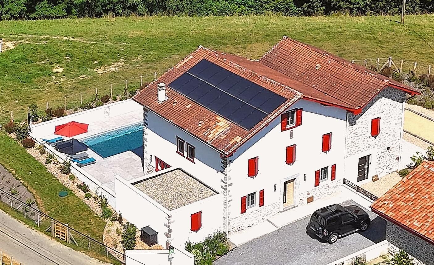 A two-story house with a swimming pool, solar panels, and a parked car.
