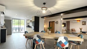 A modern kitchen with a large island, a dining area with a wooden table and colorful chairs, and a living area with a sofa and a TV. - KURUTXETA - LASSE - Gîte (LASSE)