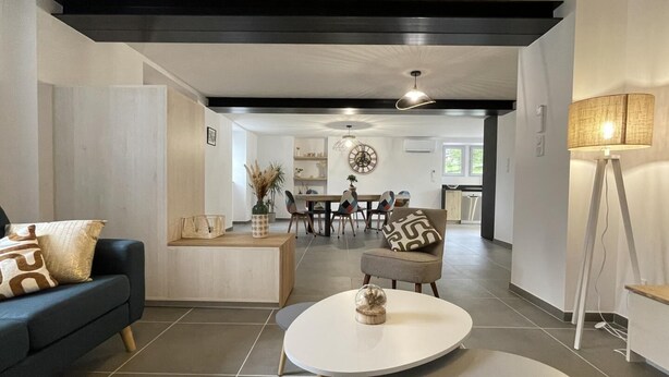 A modern living room with a sofa, coffee table, and dining area in the background. - KURUTXETA - LASSE - Gîte (LASSE)