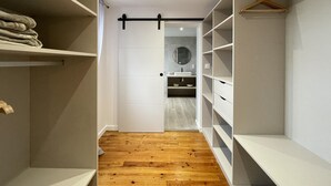 A walk-in closet with wooden flooring, white shelving, and a hanging rod. - KURUTXETA - LASSE - Gîte (LASSE)