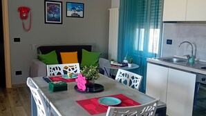 A modern kitchen with white cabinets, a stainless steel sink, and a dining area with a table set for two.