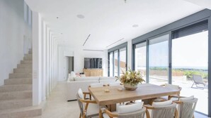 Amplia sala de estar con una mesa y sillas de madera, un sofá, y un ventanal con vistas al exterior.