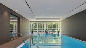 An indoor swimming pool with clear glass walls, a metal ladder, and potted plants. - Das Affalterbach, Stuttgart, Autograph Collection (Affalterbach)