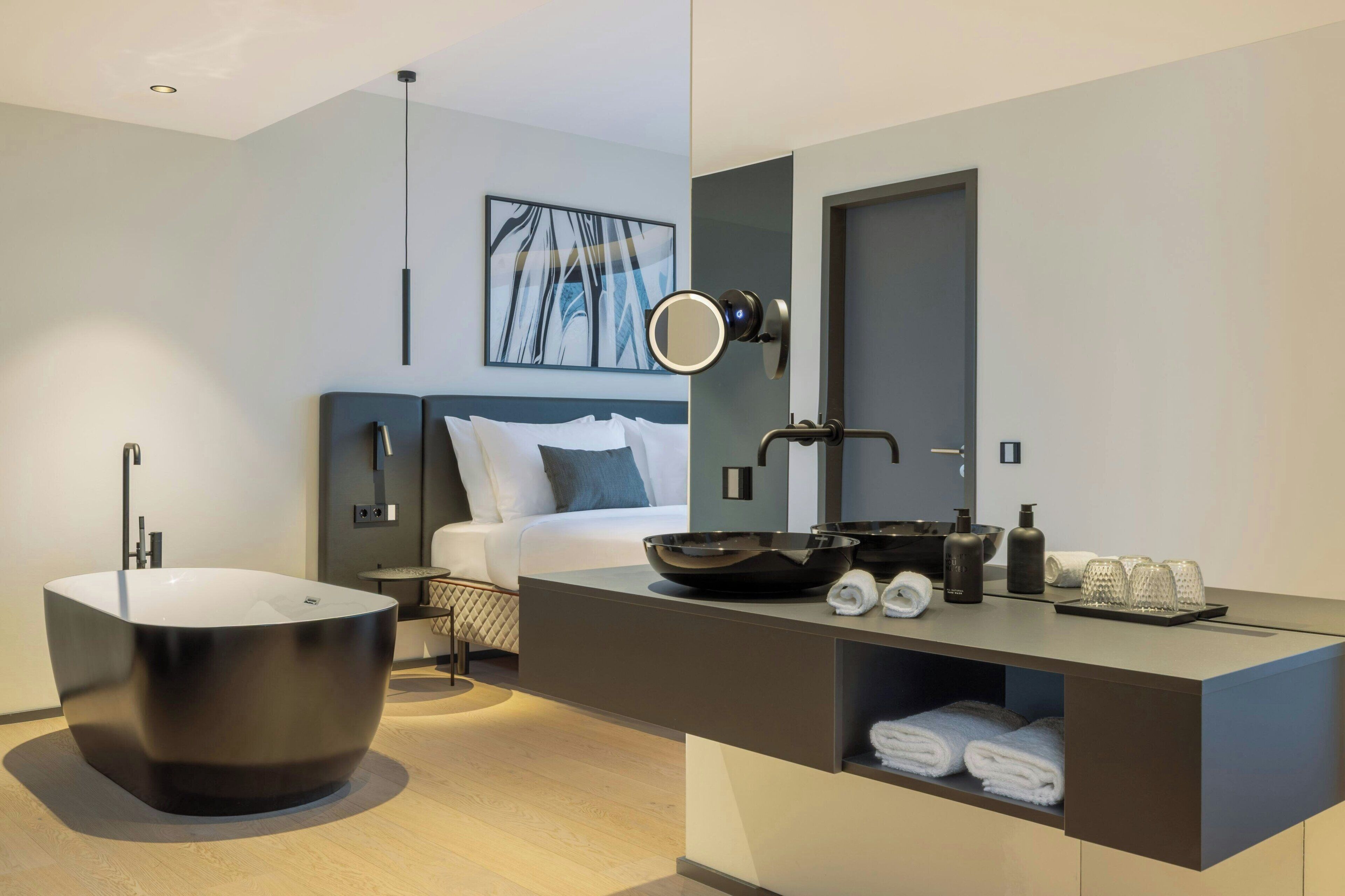 Ein modernes Badezimmer mit einer freistehenden Badewanne, einem Waschtisch mit Spiegel und ordentlich drapierten Handtüchern.