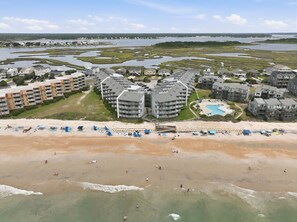 An aerial view of a coastal resort with multiple high-rise buildings, a sandy beach, and a large body of water. - Clean, Oceanfront Condo w/ Pool Access, King Suite, Bunks & Beautiful Views! (North Topsail Beach)