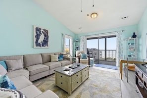 Ein Wohnzimmer mit Sofa, Couchtisch und Kunstwerken. Es gibt einen Balkon mit Blick.
