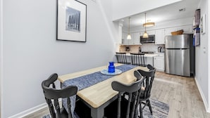 A modern kitchen with white cabinetry, stainless steel appliances, and pendant lighting. - Clean, Oceanfront Condo w/ Pool Access, King Suite, Bunks & Beautiful Views! (North Topsail Beach)