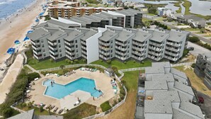 Ett hotell med flera våningar, en pool, direkt tillgång till stranden och utsikt över ett kustnära område.
