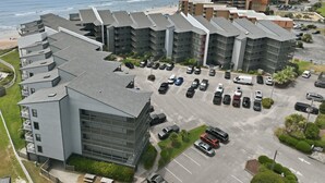 A multi-story hotel with a parking lot, beachfront view, and modern architecture. - Clean, Oceanfront Condo w/ Pool Access, King Suite, Bunks & Beautiful Views! (North Topsail Beach)