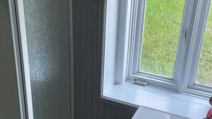 Un baño con ventana, lavamanos y un perchero para toallas.