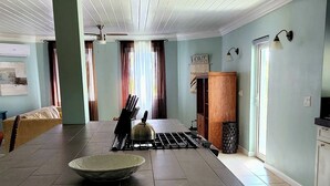 Eine geräumige Küche mit einer zentralen Kochinsel, ein Essbereich mit einer Couch und Blick zum Wohnzimmer.