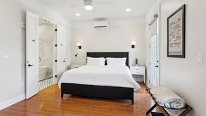 A modern bedroom with a black bed, white walls, a ceiling fan, recessed lighting, a bedside table with a lamp, and a framed picture on the wall. - The Basin Suite- French Quarter Views! (New Orleans)